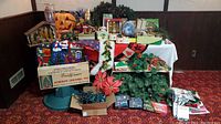Overview of seasonal lot on table showing aluminum Christmas tree box and stand, garlands, gift wrap, lights, nativity stable, pumpkins