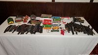 Top view of full lot showing toy train cars, plastic and metal tracks, buildings, batteries, and accessories spread on table