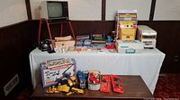 Overview of two tables showing Meccano parts, Bake-O-Matic oven, View-Master, GE record player, Tonka RV and other items