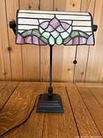 Front view of the stained glass banker's lamp showing the floral design on the shade and black metal base