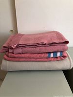 Stack of three wool blankets: two pink and one beige, showing texture and size proportions