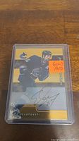 Photo showing a hockey trading card of Ed Jovanovski with gold autograph, encased in protective plastic holder.