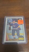 Close-up of Luc Robitaille rookie hockey card in protective sleeve, player shown skating in blue and yellow Kings uniform, RC sticker on card.