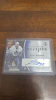 Front view of autographed Mikael Tellqvist hockey card in plastic holder on wood surface.