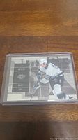 Photo of a Wayne Gretzky hockey card in protective plastic sleeve on a wooden surface.