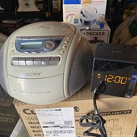 Sony CD Radio and Alarm Clock Radio side by side on a box showing condition and model details