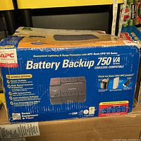 Front view of the APC Battery Backup box showing product name, specifications, and features.