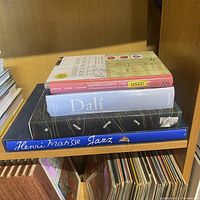 Four books stacked on a shelf: 'Understanding Voice Problems', sealed 'Dali' book, a black book, and 'Henri Matisse Jazz'.