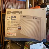 Photo of the packaged Kenmore True HEPA Air Cleaner from the front, showing brand, model, and key features like particle removal and recommended room size.