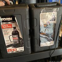 Photo showing front of two black hard carrying cases for the Torin 12 ton hydraulic bottle jacks with label and specifications visible.