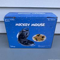 Original blue box of Mickey Mouse waffle maker with product image showing opened waffle maker and a Mickey-shaped waffle with fruit