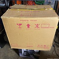 Front view of the original sealed cardboard box with printed handling instructions and branding.