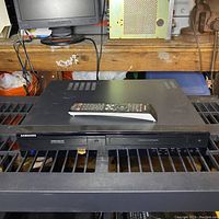 Full front view of Samsung DVD recorder VCR combo with remote on top, showing device and front panel details