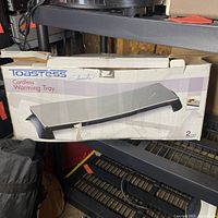 Box packaging for Toastess Silhouette cordless warming tray with visible wear and tear