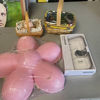 Lot items shown on gray surface: two small Longaberger baskets with fabric liners, pink flower light wrapped in plastic, boxed silver toilet paper holder