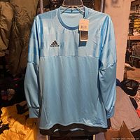Front view of light blue Adidas goalkeeper jersey shirt with tags on hanger.