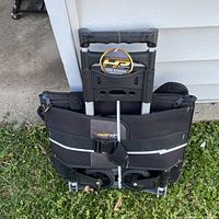 Folded rolling tool storage bag with wheels, black fabric, and extendable handle with brand tag visible.
