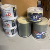 Three spindle packs of Fujifilm DVD+R discs stacked, showing 50 discs each with 4.7GB capacity and 16x speed.