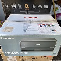 Closed Canon PIXMA iP3000 printer box with product image and specifications visible on front and top, box shows tape and wear.