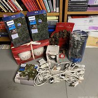 Overview photo showing Philips LED light boxes, Rae Dunn sugar and creamer set, Ravens Gnome ornament box, pine cone garland, and various light cords on table.