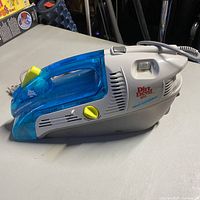 Side view of Dirt Devil Spot Scrubber vacuum cleaner showing blue translucent dust compartment and yellow control buttons.