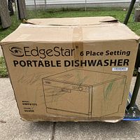 Photo showing front of box with EdgeStar branding, model DWP61ES, 6 place setting portable dishwasher printed in black lettering on brown cardboard box. Box is worn.