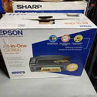 Original Epson CX7400 all-in-one printer box with product image and features highlighting print, copy, and scan functions. Also visible are system requirements for using the printer with Windows and Macintosh systems.