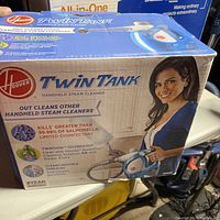 Box of Hoover Twin Tank handheld steam cleaner with product information and marketing details visible.