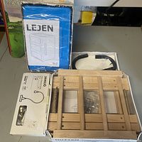 Overview photo showing boxed Lejen Storage, Jansjo Lamp box, Hutten wooden rack partially visible, and black curved Knolfly wall mount pieces