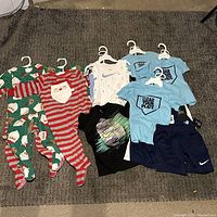 Overall spread of all 9 clothing pieces on carpet including Christmas pajamas and Nike activewear.
