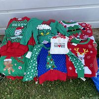 Photo showing 9 colorful Christmas themed children's sweaters and one white shirt, all new with tags