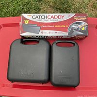 Closed Wahl clipper cases and boxed Catch Caddy on red surface outdoors