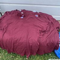 Pile of maroon red shirts showing front view folded together