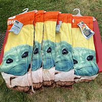 Five Star Wars Mandalorian Baby Yoda beach towels folded on a red surface with the character image partially visible.