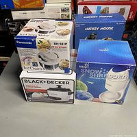 Photo showing all three boxed items; Panasonic ice cream maker, Black+Decker rice cooker, HawaiIce snow shredder.