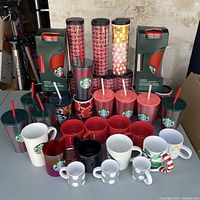 Photo of Starbucks ceramic mugs, cold cups, and insulated tumblers arranged on table showing variety of colors and designs
