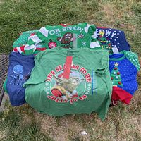 Six Christmas and Star Wars themed sweaters and T-shirts laid on grass showing various designs and colors