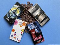 Photo of four ChocChique artisanal chocolate bars arranged over cocoa beans, showing distinct colorful packaging designs for each bar.
