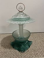 Front view of the one-of-a-kind bird feeder assembled from vintage glassware with metal hanging loop on top.