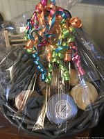 Front view of wrapped gift basket showing soaps, sponge, and container inside with colorful ribbons.