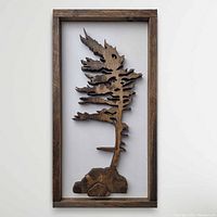 Full front view of the hand scrolled pine tree silhouette mounted in a wooden frame on a white background.
