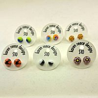 Photo of 6 pairs of colorful round handmade glass stud earrings mounted on white cards labeled 'Karen Reece Designs' with $10 price tags.