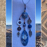 Full view of the pendant necklace with multiple dangling elements, showing blue and silver tones against a white cloth background.