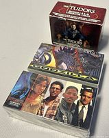 Box and front faces of The Tudors open collector card box and two sealed trading card packs for Godzilla and Independence Day movies.