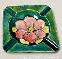 Top close-up of square ceramic ashtray with green glaze and pink flower center