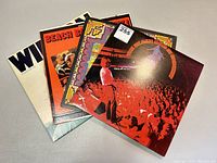 Four Beach Boys record albums stacked showing front covers with various designs and colors.
