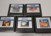 Five Atari 2600 game cartridges with visible labels showing PAC-MAN, Ms. PAC-MAN, CENTIPEDE, FOOTBALL, and BASEBALL titles.