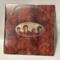 Front cover of The Beatles 'Love Songs' double album showing brown textured sleeve with an oval containing portraits of the band members and album title.