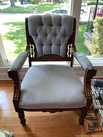 Front view of Victorian style armchair showing tufted backrest, upholstered seat, and carved wood frame.