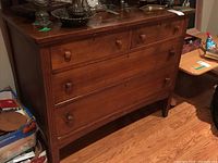 Front view of vintage wooden dresser showing four drawers with wooden knob handles and some visible wear.